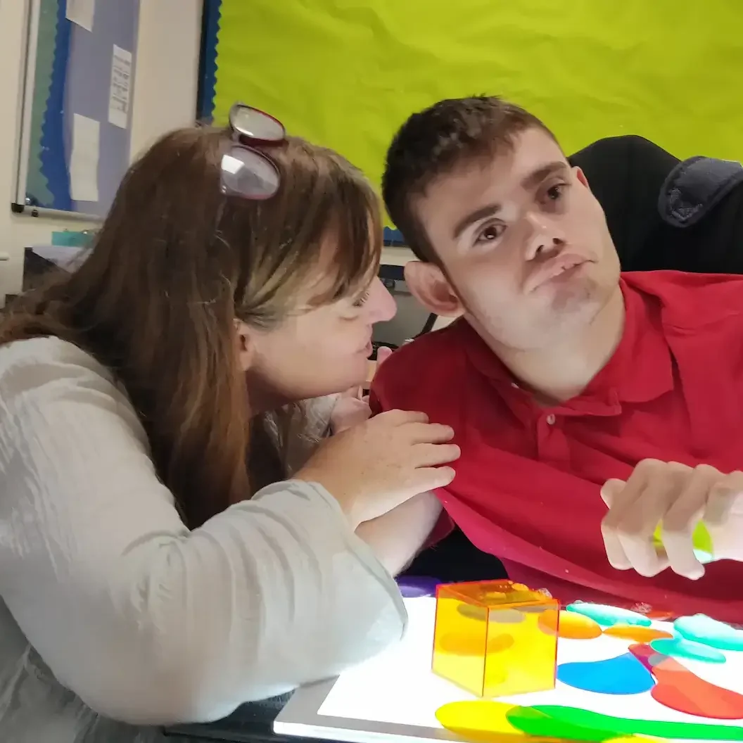 2) A support worker actively listening to someone in a safe, sensory-friendly space