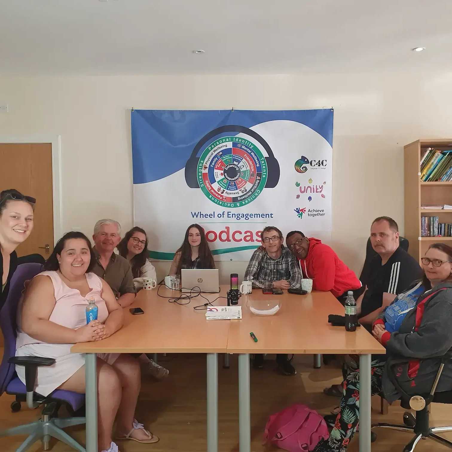 podcast team around table with Wheel of Engagement behind them podcast team around table with Wheel of Engagement behind them